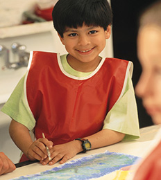 Male student wearing a smock participates in a painting activity
