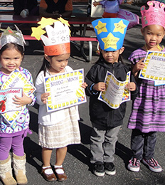 Four students wearing paper crowns hold their award certificates