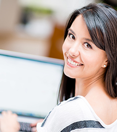 Smiling woman using a computer looks over her shoulder
